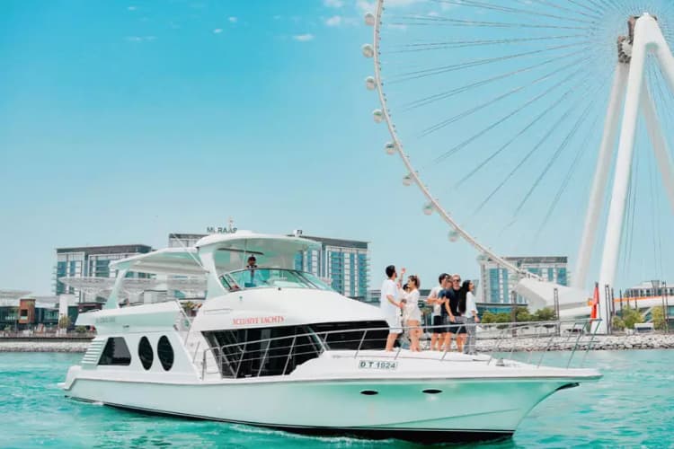 A white yacht sails in bright blue waters with several people on deck, enjoying the view.