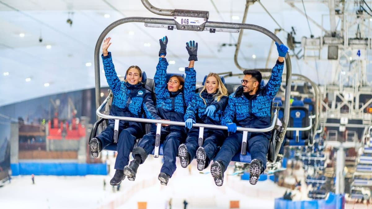 Visitor riding the indoor zip line above the snowy slopes at Ski Dubai.