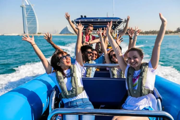 A group of happy people on a speedboat, raising their hands in excitement. 