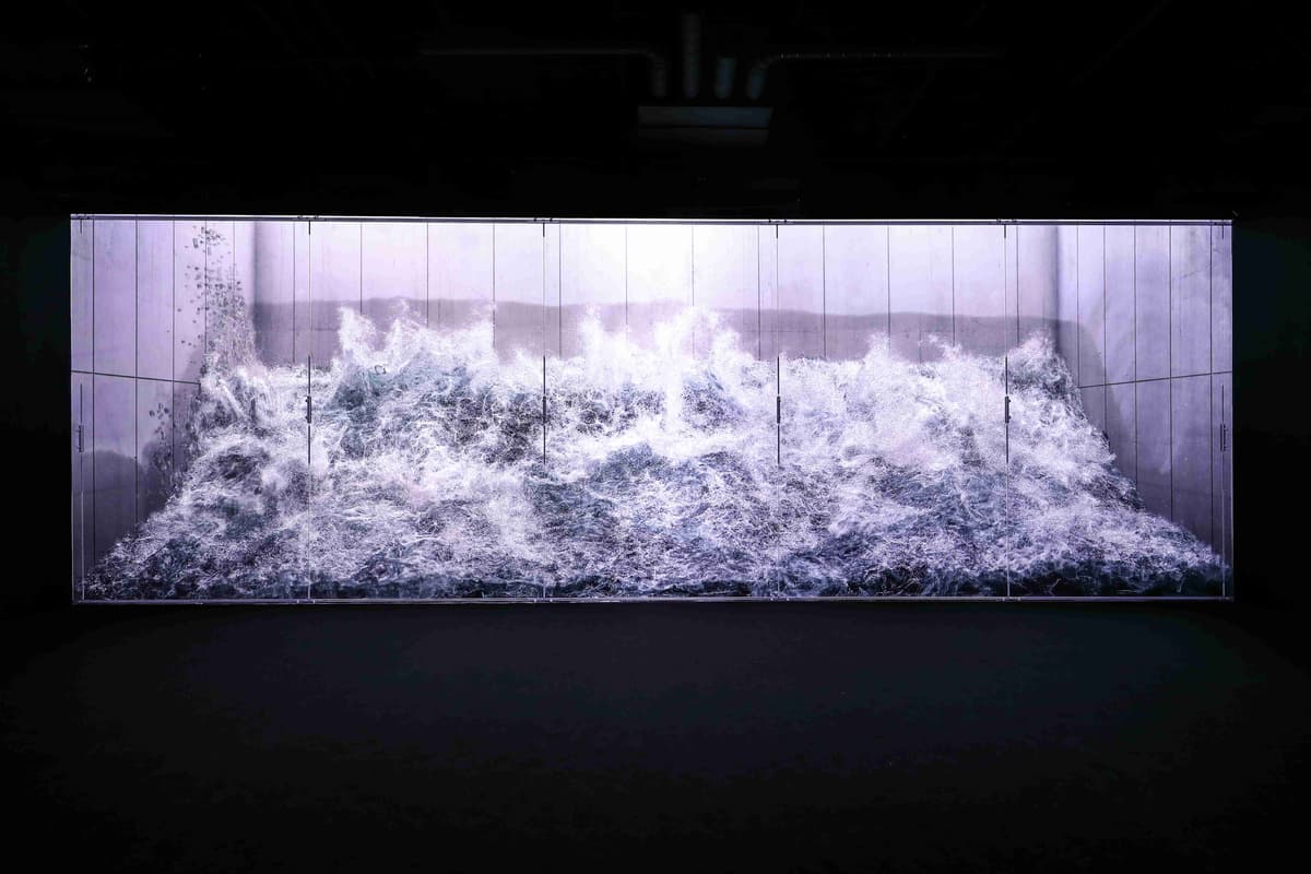 A large screen displays waves crashing into the ocean at the Arte Museum's "White Light" exhibition.
