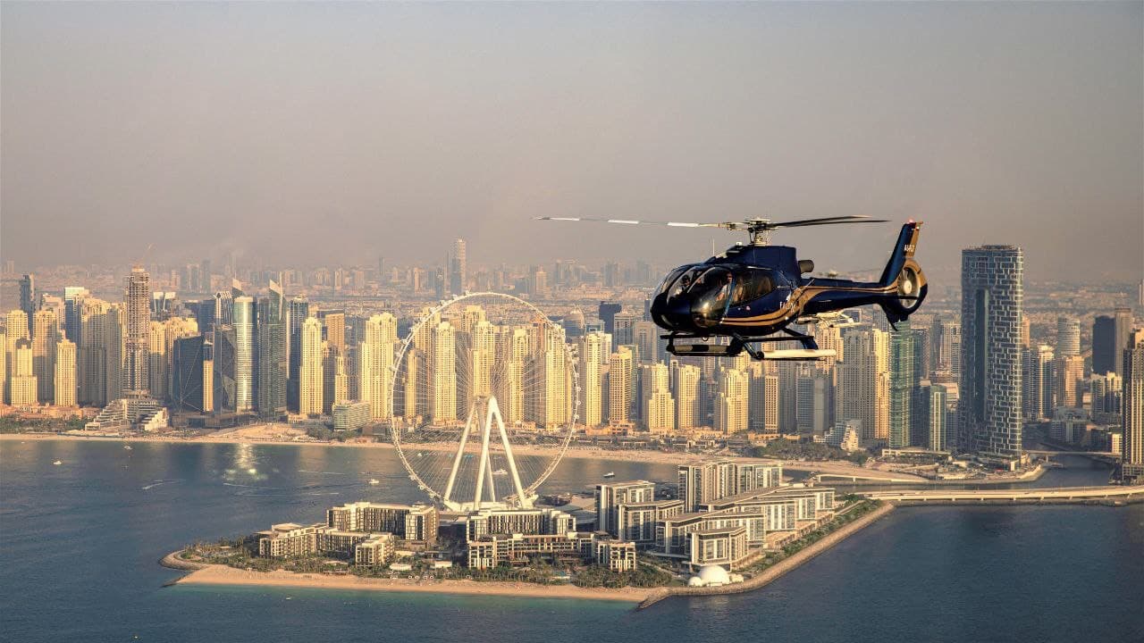 A black helicopter flies over Dubai's coastline