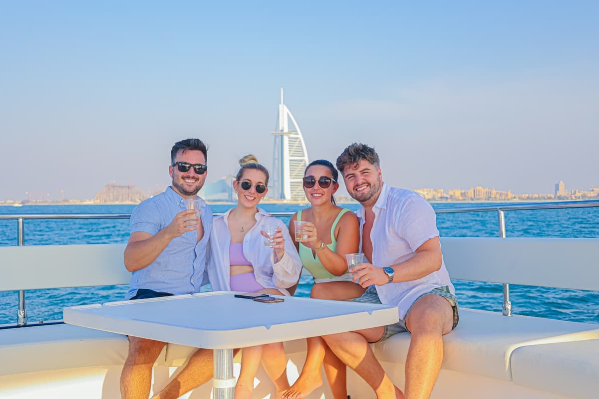 Four people enjoying a glass of wine while sitting on a boat during the Burj Coastline Tour group photo.