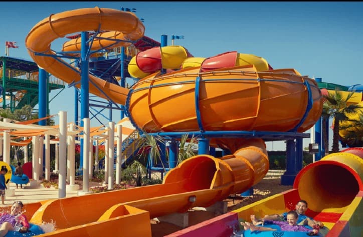 A vibrant water park scene featuring large, twisting orange and yellow slides.