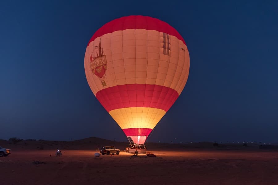 Hot air balloon flying over the Dubai desert at sunrise during a thrilling morning adventure.