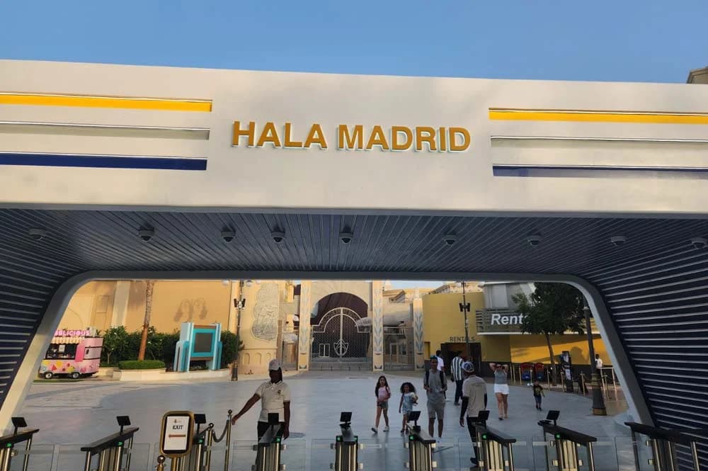 Entrance with "Hala Madrid" sign, featuring blue and yellow accents. People are passing through
