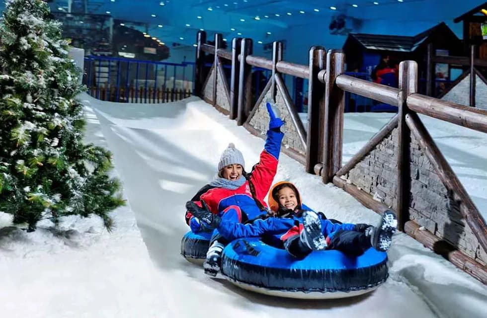 Visitors enjoying snow rides and winter activities inside Ski Dubai indoor snow park.