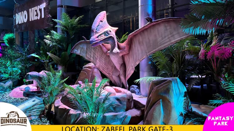 Life-size dinosaur models displayed in a themed outdoor Dinosaur Park with visitors exploring the attraction.