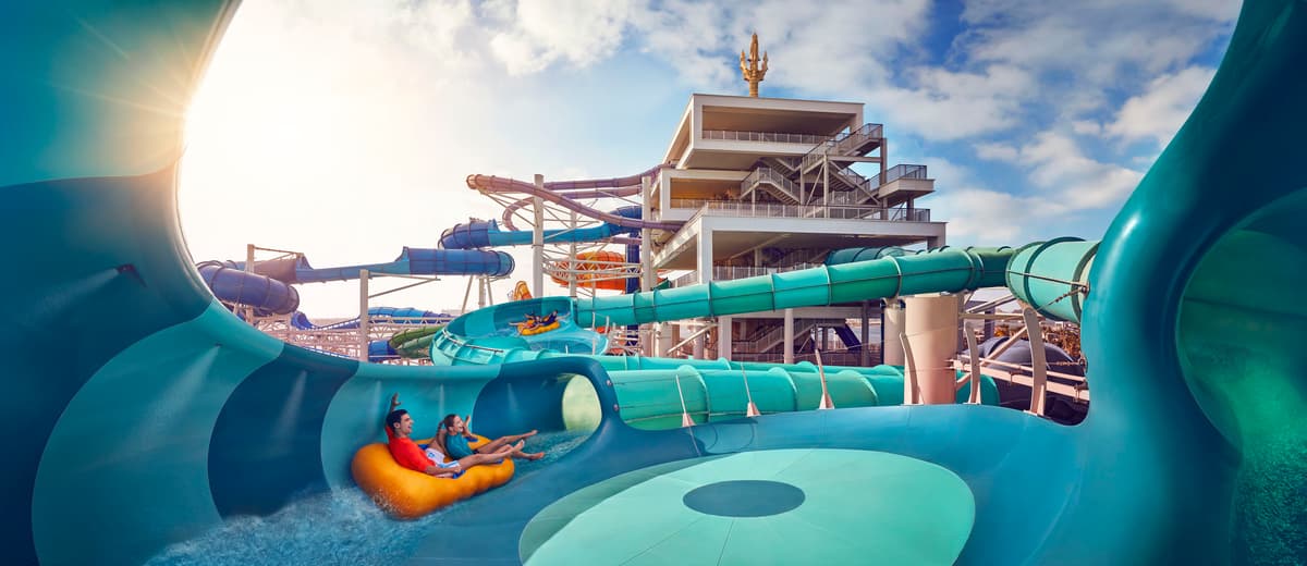A colorful water slide at Atlantis Aquaventure, surrounded by lush greenery and the Lost World Aquarium