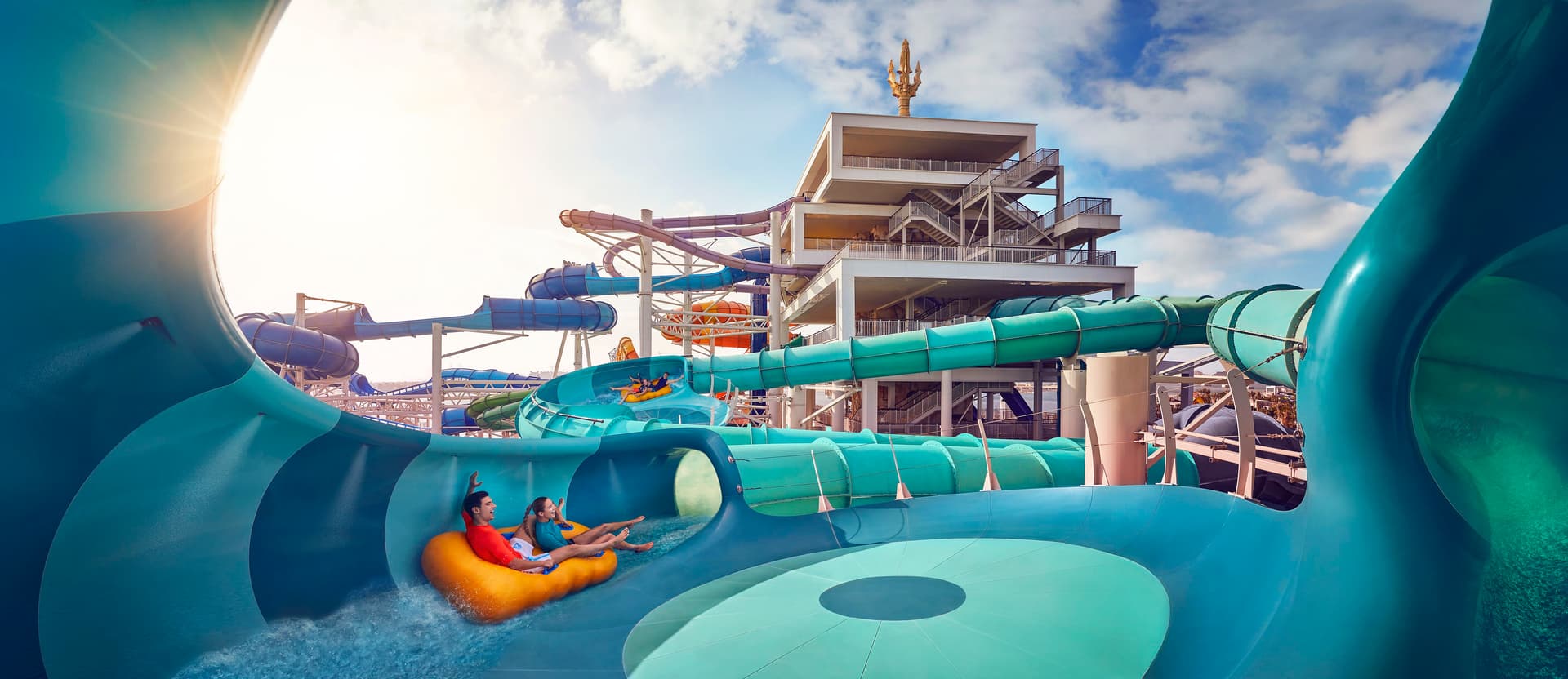 A colorful water slide at Atlantis Aquaventure, surrounded by lush greenery and the Lost World Aquarium