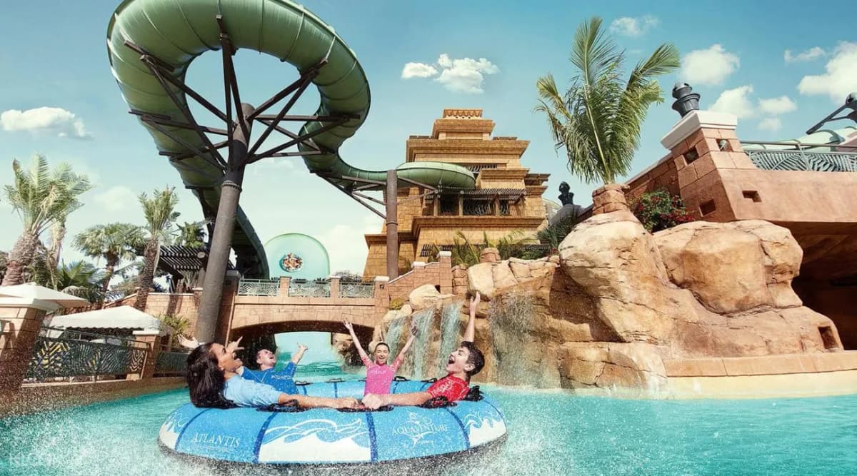 A family joyfully rides a water slide at Atlantis Aquaventure, surrounded by splashes and excitement at the water park.