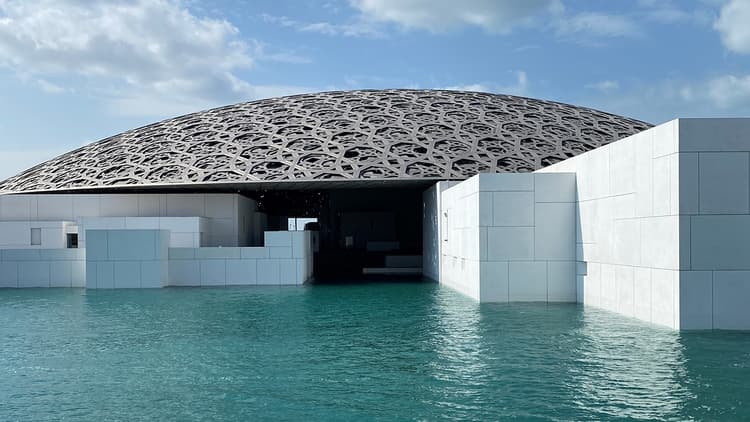 Modern architecture of Louvre Abu Dhabi featuring sleek lines and innovative design against a clear blue sky.