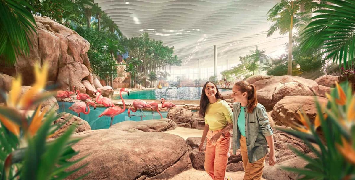 Two girls walk through the Tropical Ocean indoor pool at SeaWorld Abu Dhabi, surrounded by colorful flamingo decorations.