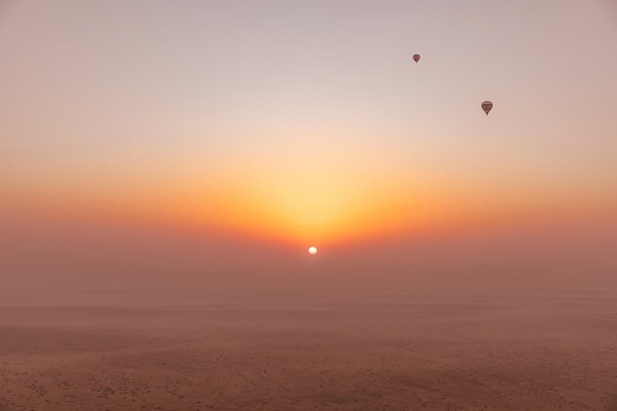 Hot air balloon floating over the Dubai desert during a beautiful sunrise.