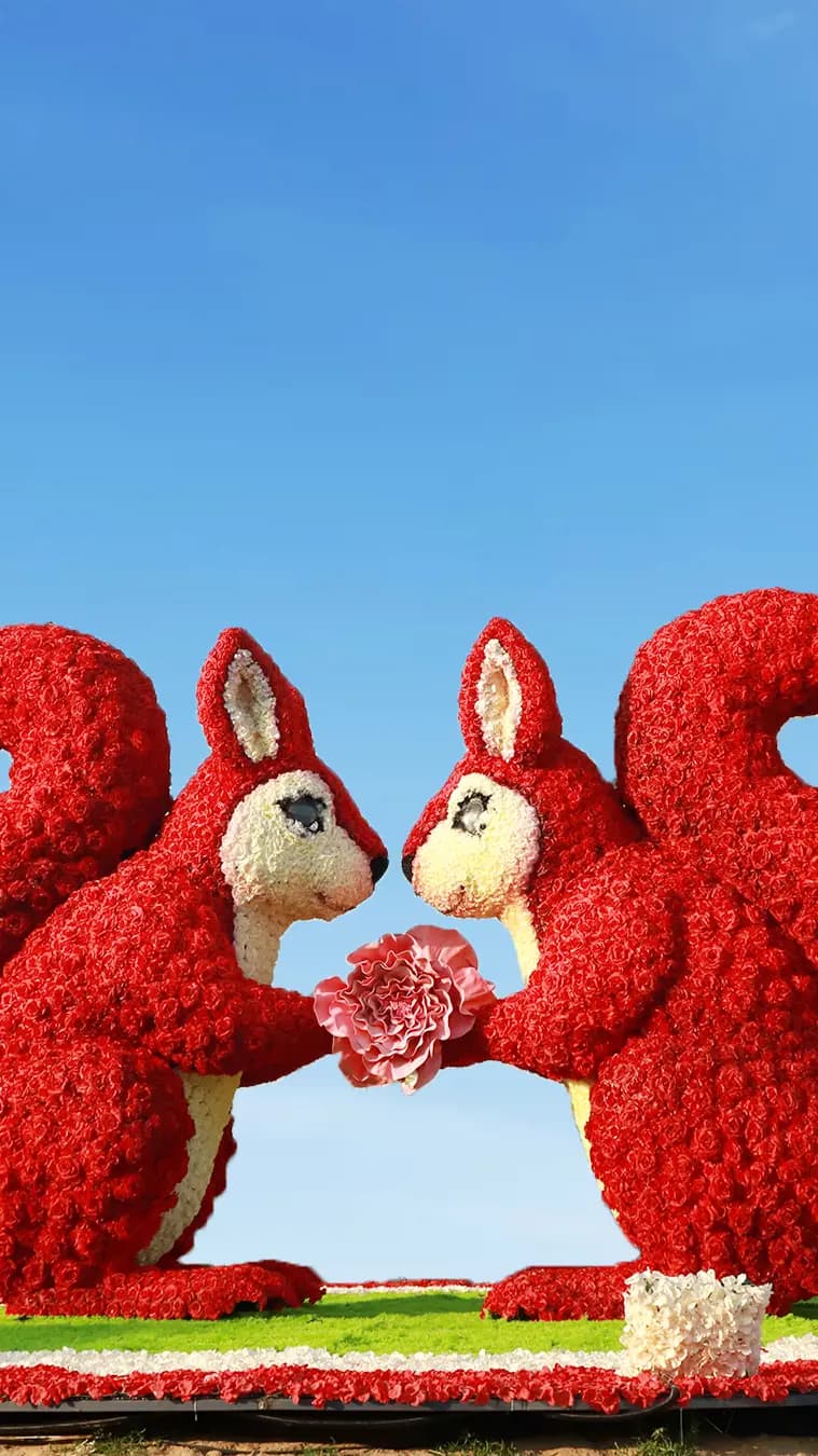 Two squirrel figures forming a heart symbol in a colorful light display at Dubai Garden Glow.