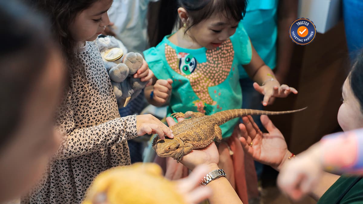 Kids experiencing and gently touching small animals during an interactive encounter at The Green Planet Dubai.
