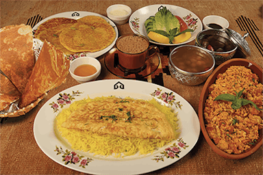 A lavish spread of Middle Eastern dishes on a table, including flatbreads, eggs with rice, porridge, salad, and sauces