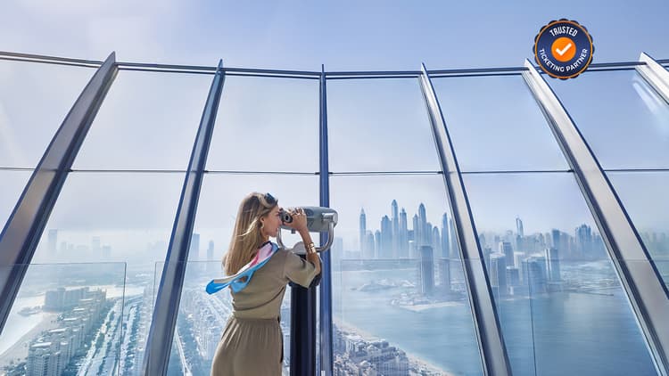 Guest using a telescope to view Palm Jumeirah from The View observation deck