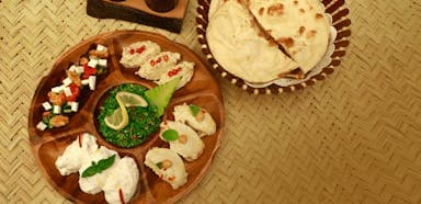 Wooden platter with assorted dips: white, red-speckled, herb-topped. 