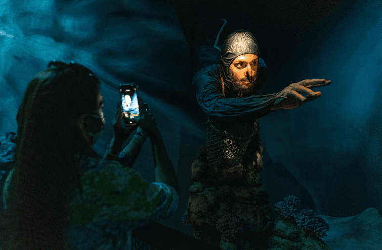 A woman photographs a statue inside the Alif aquarium at Expo City Dubai.