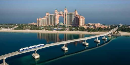 Main view of the Palm Monorail traveling across Palm Jumeirah with Dubai’s skyline in the background.