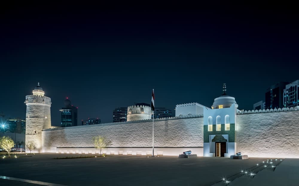 Night view of Qasr Al Hosn in Abu Dhabi illuminated with warm lights highlighting the historic fort.