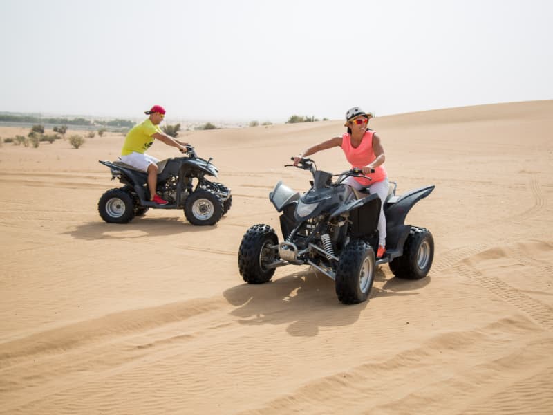 Guest riding a quad bike across the Dubai desert during the hot air balloon adventure experience