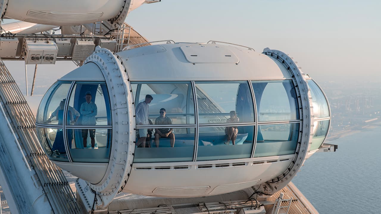 Tourists inside a glass observation capsule on Ain Dubai enjoying panoramic views of Dubai from the world's largest observation wheel.