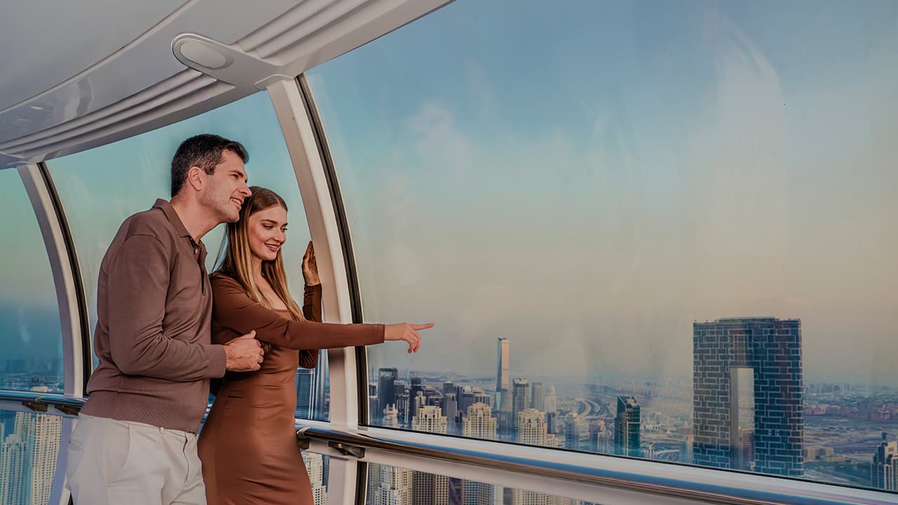 Visitors inside an Ain Dubai observation pod pointing out landmarks while enjoying 360-degree views of Dubai skyline.