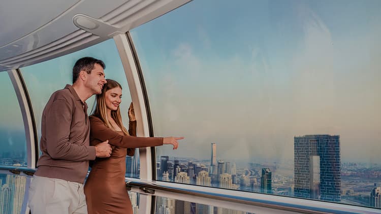 Visitors inside an Ain Dubai observation pod pointing out landmarks while enjoying 360-degree views of Dubai skyline.