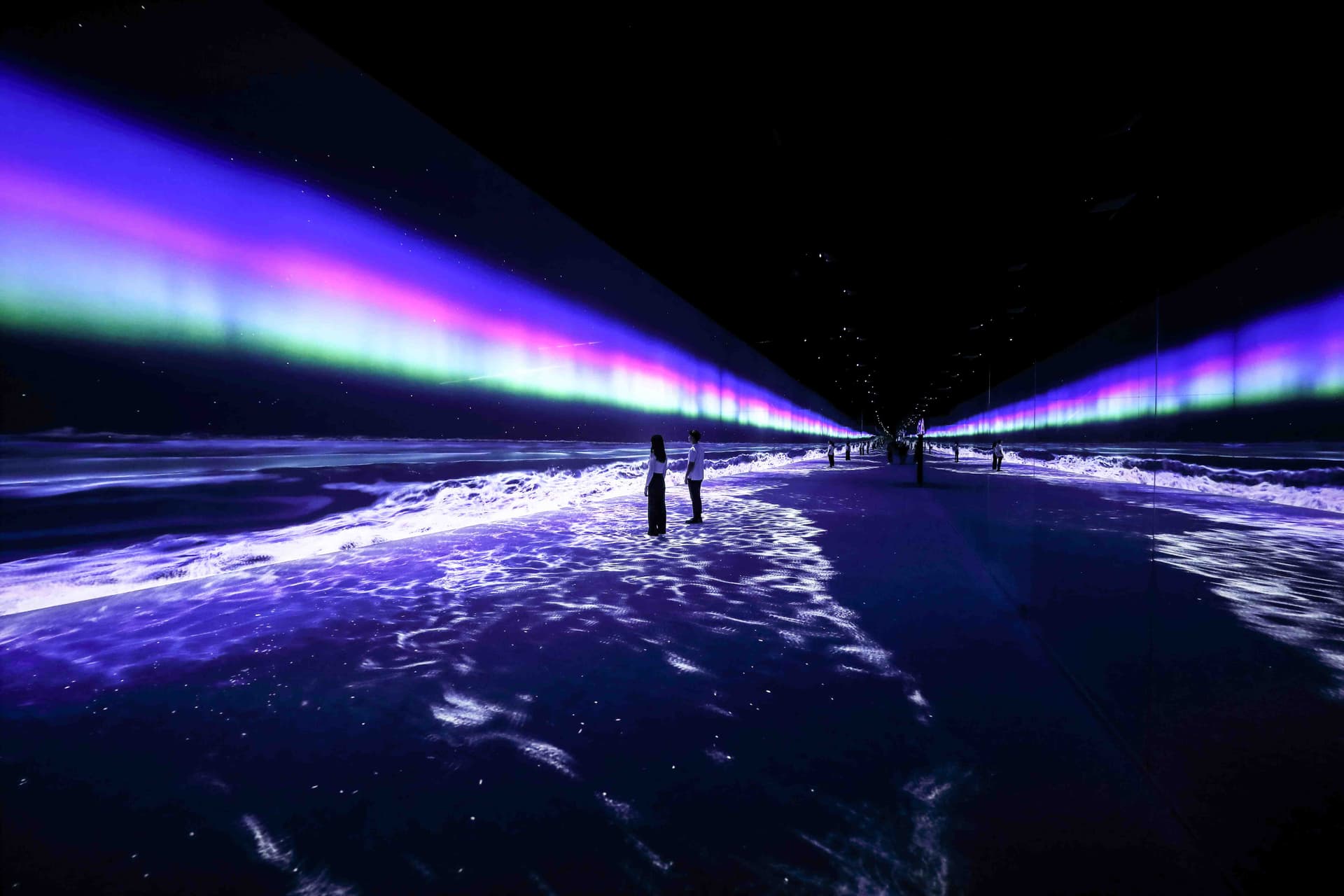 A long tunnel illuminated by lights, with water visible in the background, located in the Arte Museum - SkyLights.