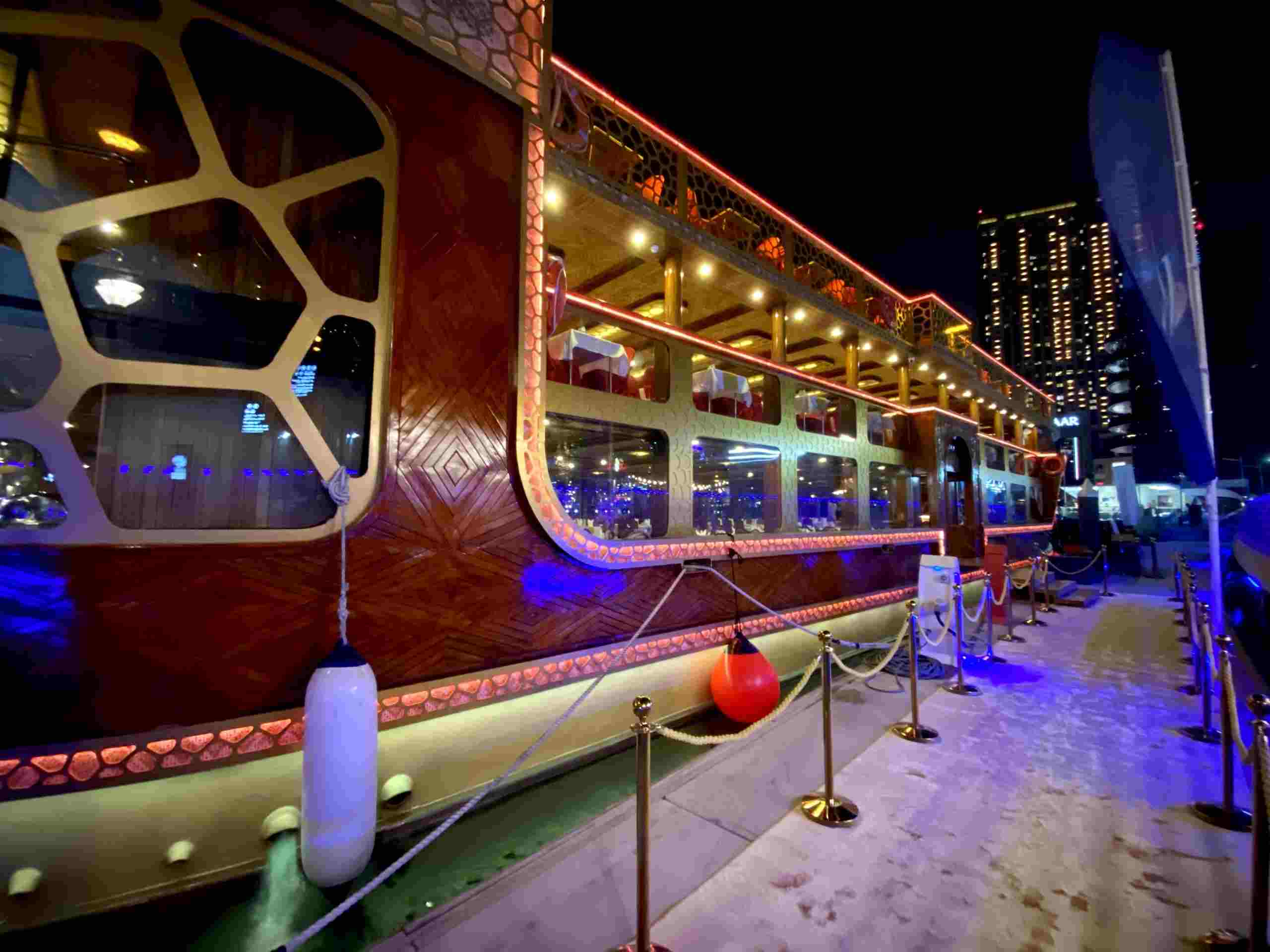 Night view of Mega Dhow dinner cruise with Dubai skyline illuminated