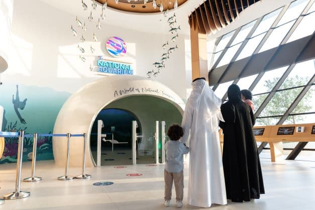 Main entrance gate of The National Aquarium Abu Dhabi with visitors arriving at the attraction