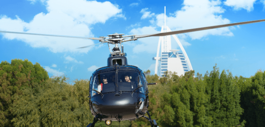 A helicopter flies over a cityscape with the Burj Al Arab visible in the background during a private tour takeoff.