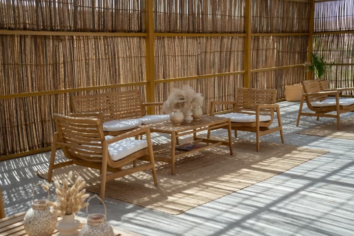 A cozy seating area featuring wooden furniture and a bamboo wall, set up for a camp dinner.