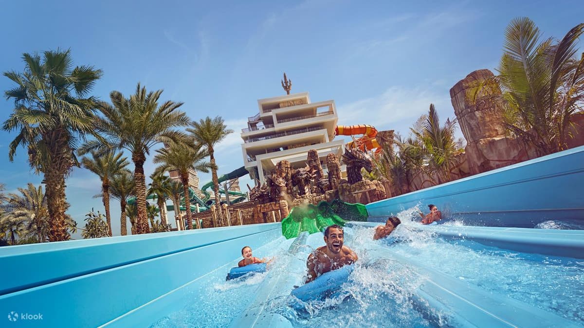 A group of people joyfully riding a water slide at Atlantis Aquaventure, surrounded by vibrant aquatic scenery.