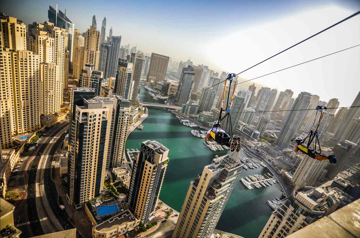 Two riders enjoying the XLine Dubai Marina double zipline experience above the city skyline