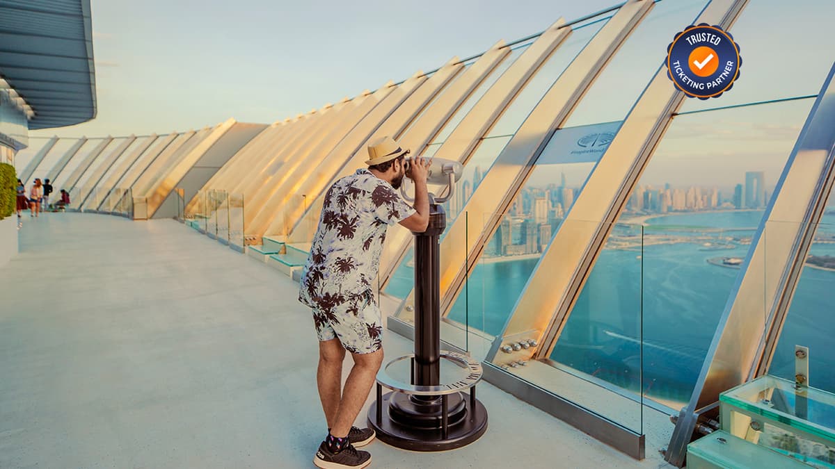 Man viewing Palm Jumeirah through a telescope from an observation deck