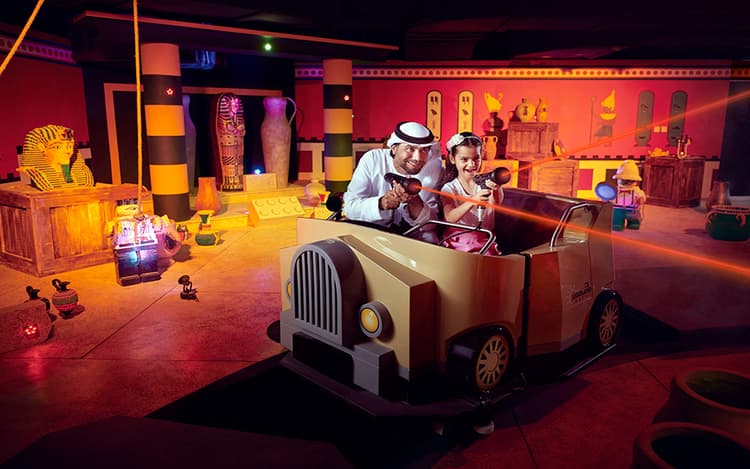 A man and a girl joyously ride in a themed adventure cart