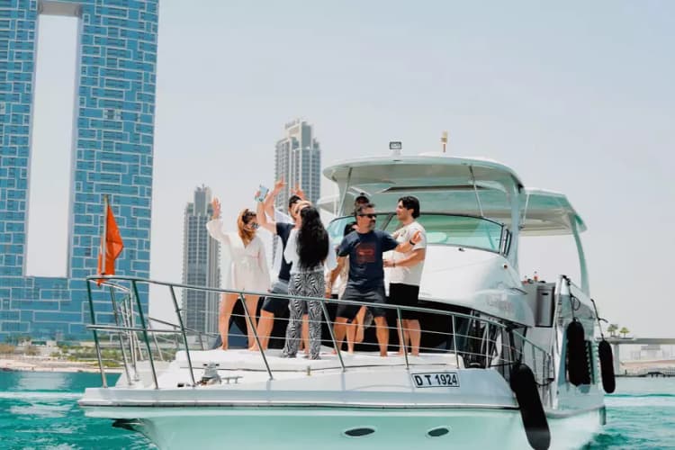 Group of friends celebrating on a yacht under a clear sky, with modern skyscrapers in the background. 