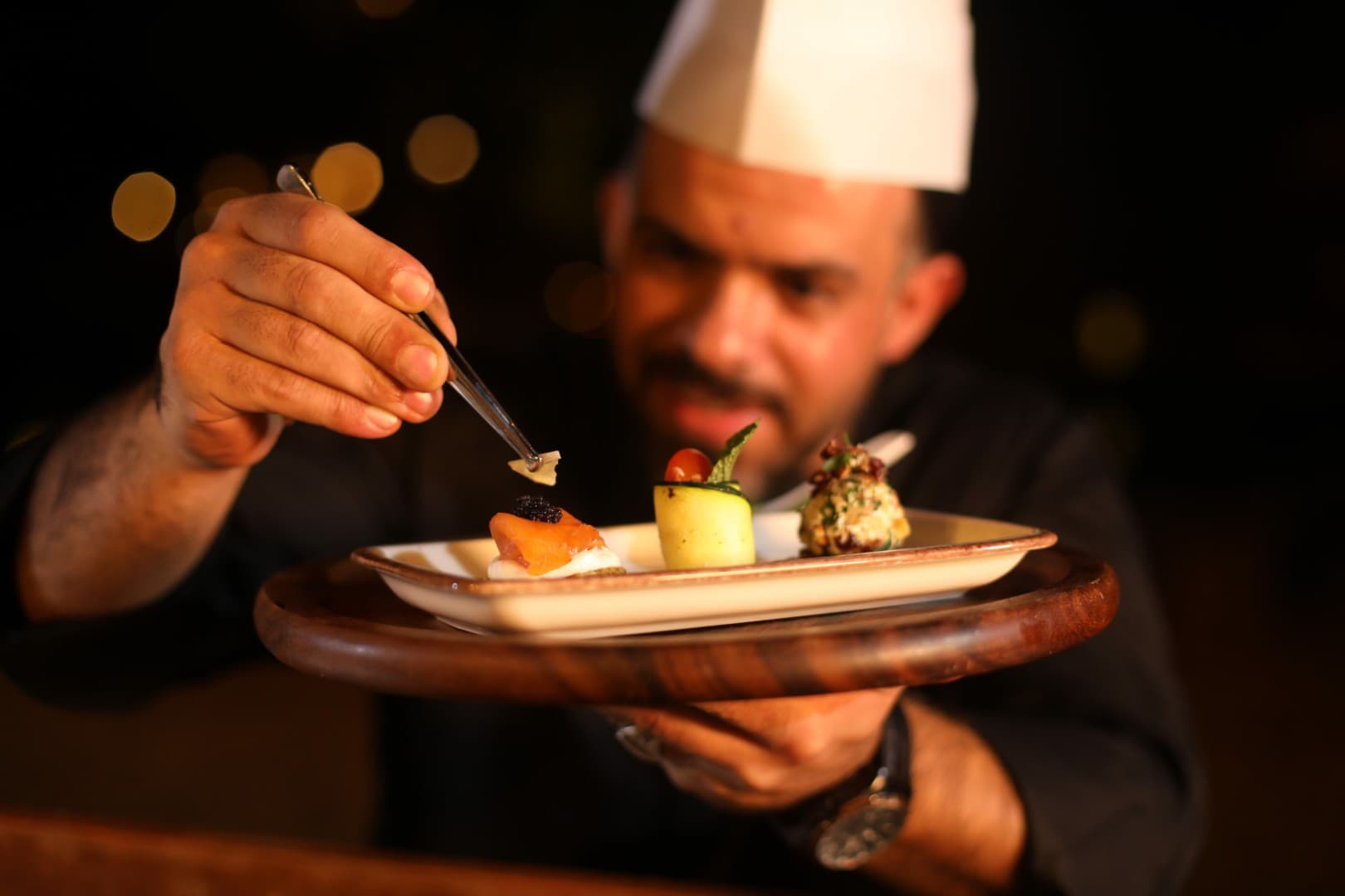 Signature gourmet dish prepared by a chef at the Platinum Desert Safari luxury dining experience in Dubai.