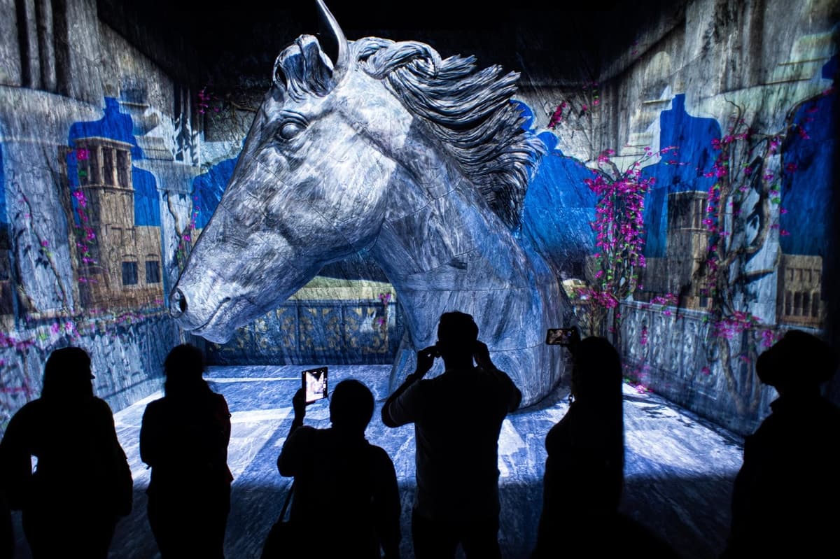 People stand in front of a horse statue at Expo City Dubai Terra, showcasing the art and culture of the event.