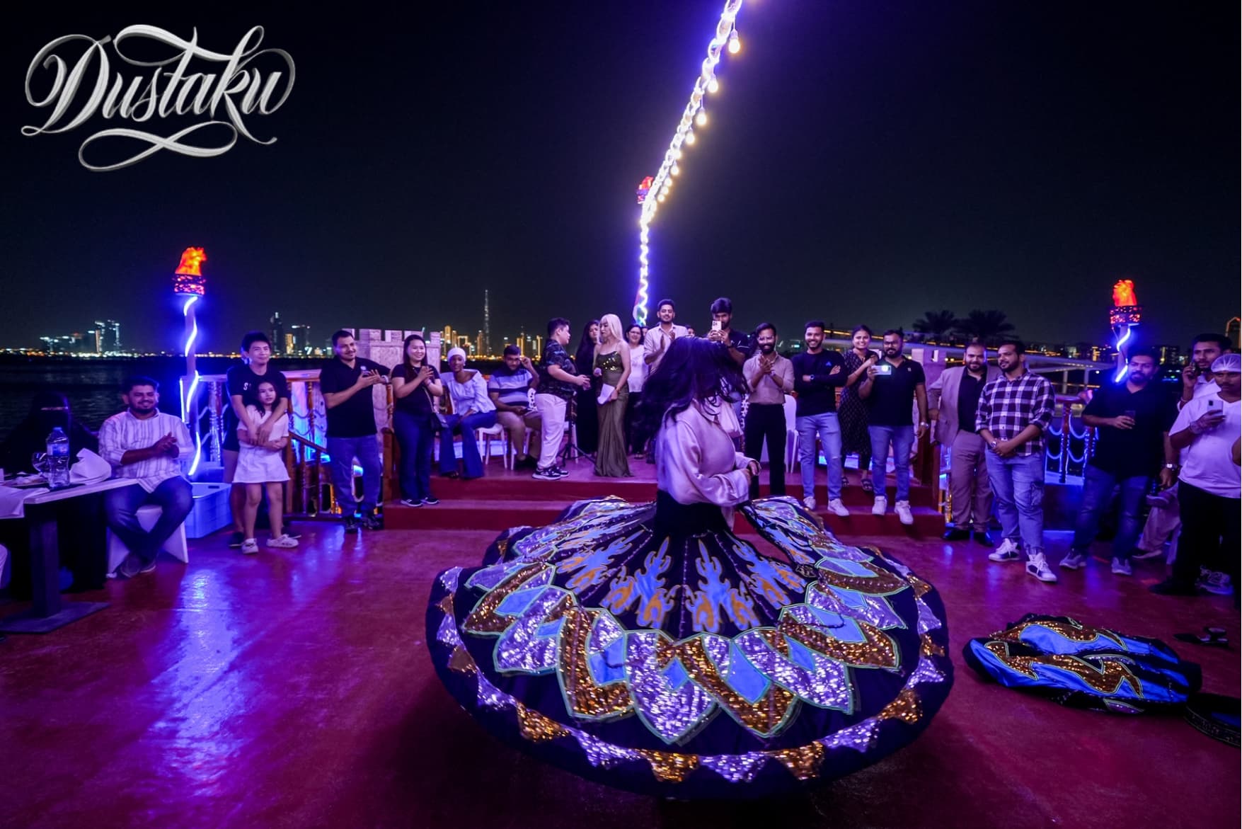 A woman in a colorful dress joyfully dances on a boat during the Dustaku Dinner Dhow Cruise activities.
