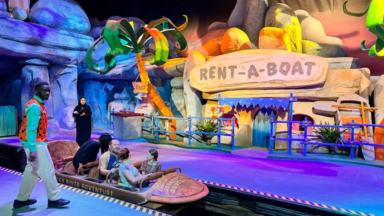 A group of people stands in front of a stage featuring a boat, engaged in conversation and enjoying the event.