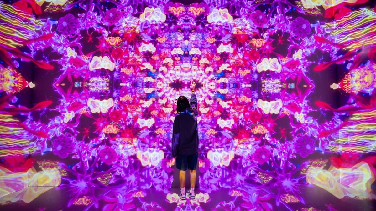 A woman poses in front of a vibrant purple flower wall at the House of Hype Dubai Immersive Experience.