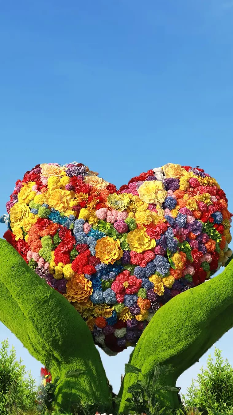 Colorful illuminated love symbol design display at Dubai Garden Glow surrounded by glowing lights.