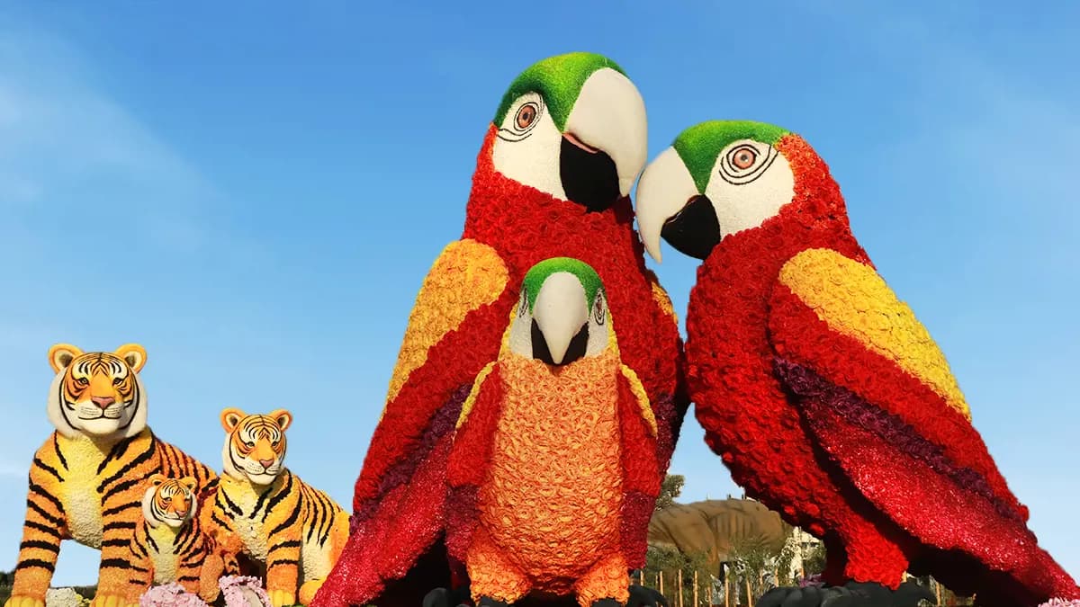 Decorative display of red parrots designed with colorful flowers and lights at Dubai Garden Glow Park.