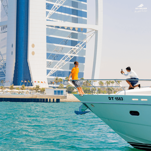 A young man capturing photos of the Burj Al Arab from a luxury cruise.