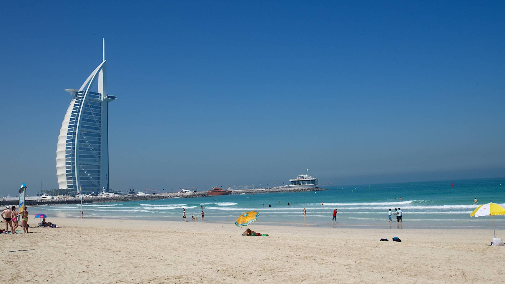Beach scene with people lounging and swimming under a bright sun. 