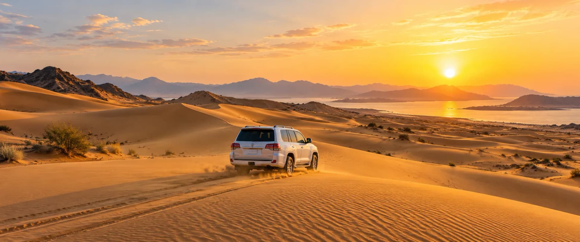 Four-wheel-drive vehicle crossing golden desert dunes