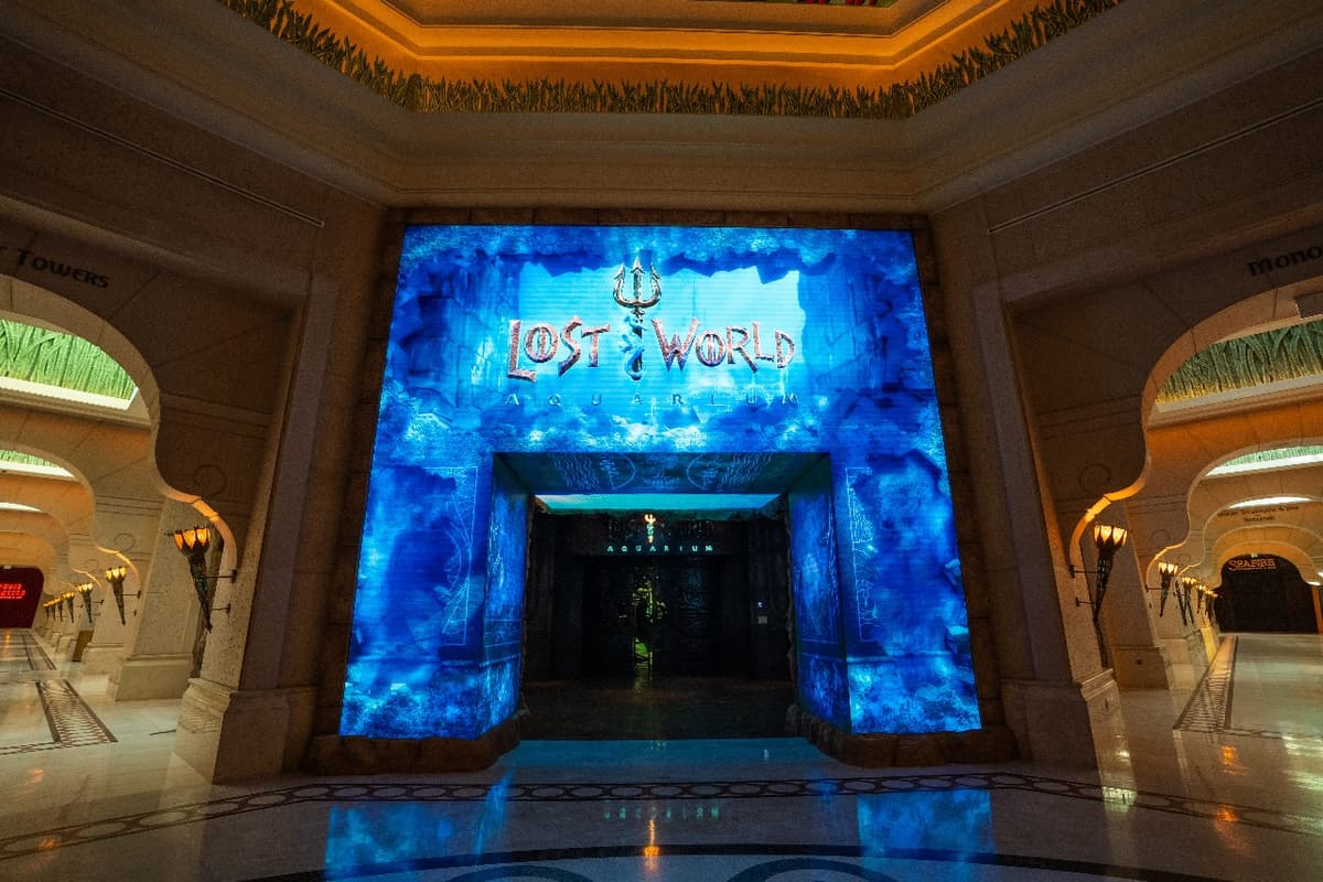 The entrance is illuminated with blue lights, showcasing its proximity to Atlantis Aquaventure and Lost World Aquarium.